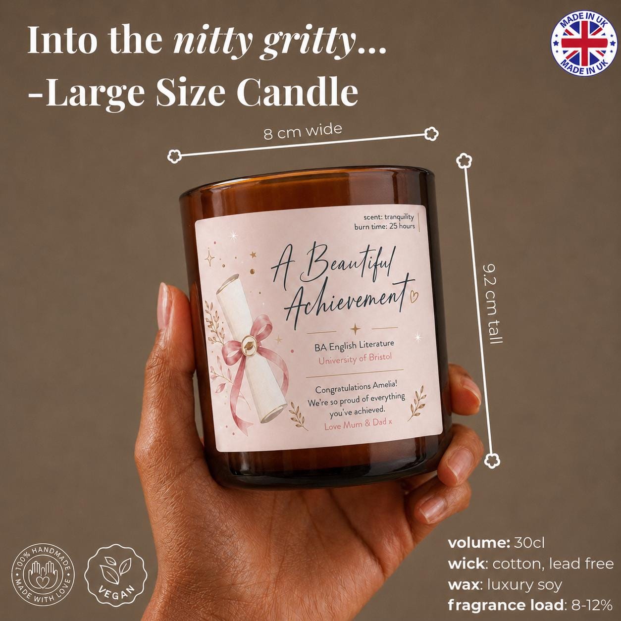 A hand holding a large glass candle labeled "A Beautiful Achievement" with a rose design.