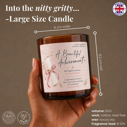 A hand holding a large glass candle labeled "A Beautiful Achievement" with a rose design.