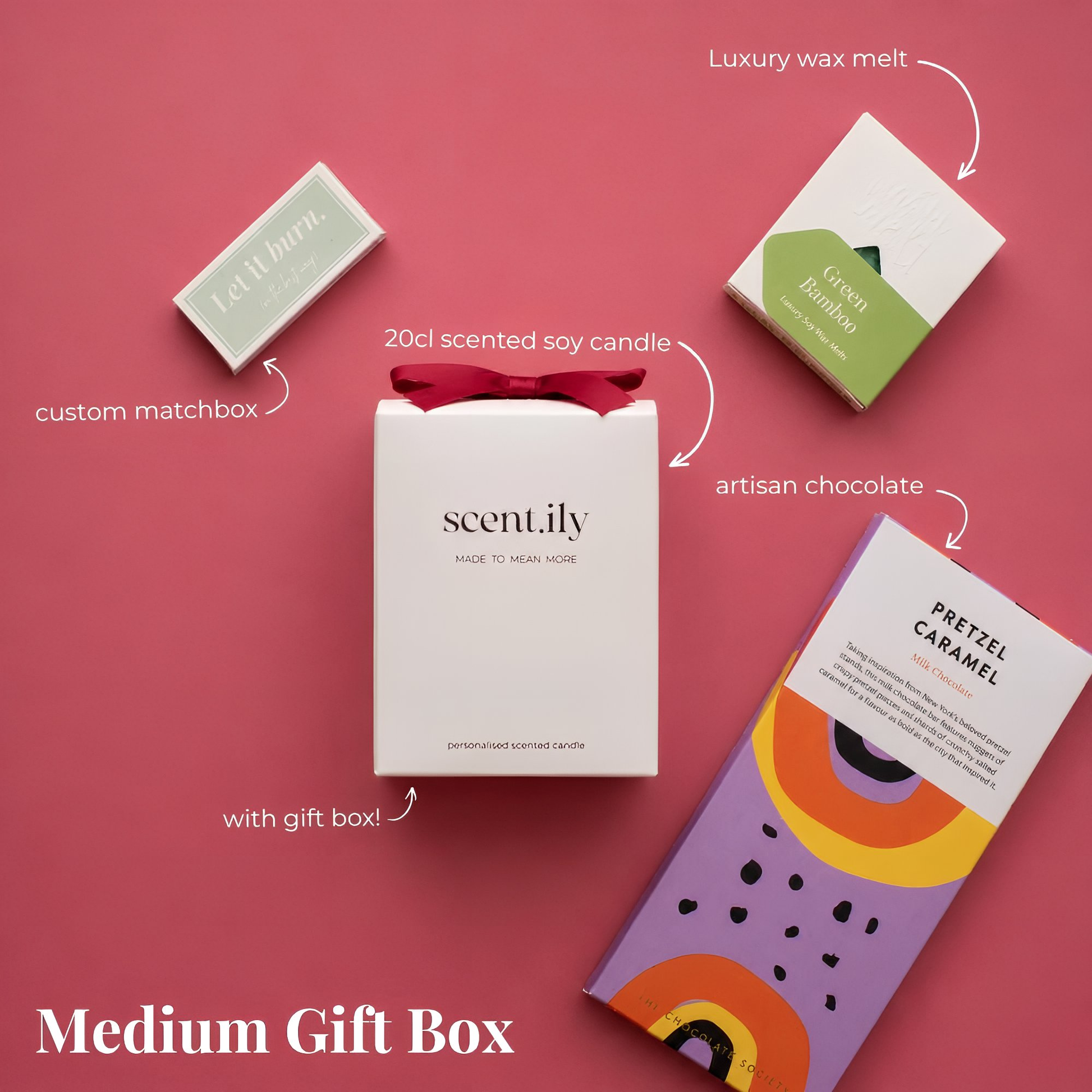 a medium-sized gift box containing various scented candles, a chocolate bar, and a pretzel.